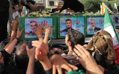 Des personnes en deuil se tenant près du cercueil du commandant du Corps des Gardiens de la Révolution islamique (CGRI) Amir Ali Hjizadeh (à gauche) et d'autres commandants militaires tués lors des frappes israéliennes le premier jour de la guerre, lors de leur cortège funèbre, sur la place Enqelab dans la capitale de Téhéran, le 28 juin 2025. (Crédit : Atta Kenare/AFP)
