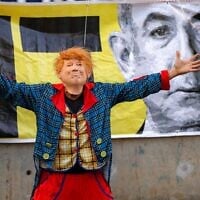 Un manifestant déguisé en clown et portant un masque représentant le président américain Donald Trump tenant une marionnette représentant le Premier ministre Benjamin Netanyahu lors d'une manifestation anti-gouvernement appelant à une action pour obtenir la libération des otages israéliens détenus dans la bande de Gaza par le Hamas depuis le pogrom du 7 octobre 2023, à Tel Aviv, le 28 juin 2025. (Crédit : Jack Guez/AFP)