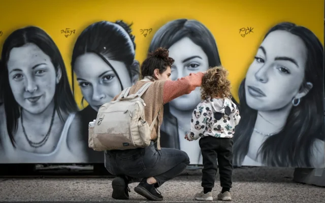 Une femme et une petite fille regardent une peinture murale représentant des soldates israéliennes prises en otage lors du pogrom du 7 octobre 2023 menée par le Hamas contre Israël, à Tel Aviv, le 18 janvier 2025. (Crédit : Oded Balilty/AP)