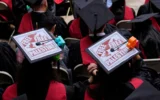 Des diplômés écoutent des orateurs tout en arborant des pancartes « Free Palestine » sur leurs chapeaux lors des cérémonies de remise des diplômes à l'université Harvard, le 29 mai 2025, à Cambridge, dans le Massachusetts. (Crédit : AP Photo/Charles Krupa)