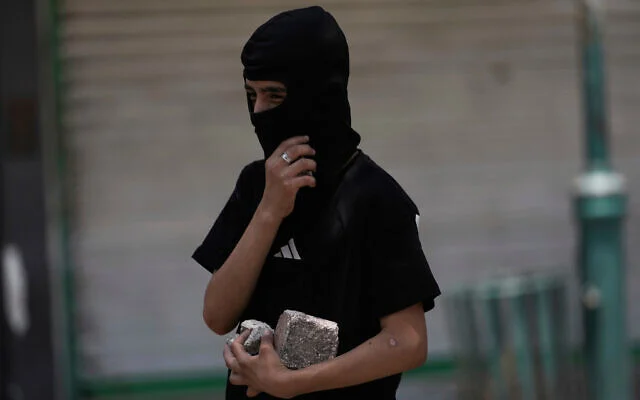Un Palestinien masqué tient des pierres lors d’affrontements avec les forces israéliennes à la suite d’une attaque militaire à Naplouse, en Cisjordanie, le mardi 10 juin 2025. (AP Photo/Majdi Mohammed) Un Palestinien masqué tient des pierres lors d’affrontements avec les forces israéliennes à la suite d’une attaque militaire à Naplouse, en Cisjordanie, le mardi 10 juin 2025. (AP Photo/Majdi Mohammed)