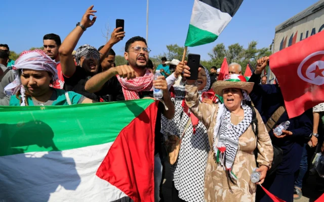 Les membres d'un convoi en route vers Gaza brandissent des drapeaux palestiniens alors que le groupe s'apprête à partir pour le passage frontalier de Rafah, en Égypte, à Zawiya, en Libye, le 10 juin 2025. (Crédit : AP/Yousef Murad)