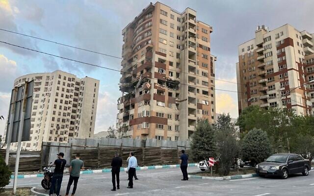 Des habitants observent un logement endommagé après des frappes israéliennes à Téhéran, en Iran, le 13 juin 2025 (AP Photo/Vahid Salemi)