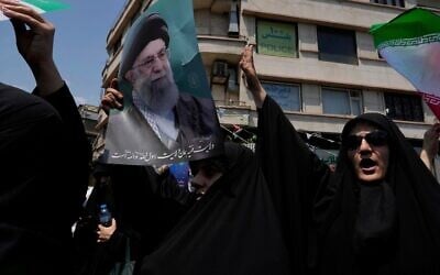 Des manifestants iraniens scandant des slogans tandis que l'un d'entre eux brandit une affiche du guide suprême, l'ayatollah Ali Khamenei, lors d'un rassemblement anti-Israël, à Téhéran, en Iran, le 13 juin 2025. (Crédit : Vahid Salemi/AP)