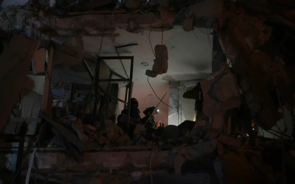 Les forces de sécurité israéliennes inspectent un immeuble détruit par un missile tiré depuis l'Iran, à Bat Yam, tôt le  15 juin 2025. (Crédit : AP/Ohad Zwigenberg)