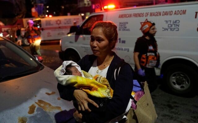 Une femme tenant un bébé dans ses bras évacue les lieux après qu'un missile lancé depuis l'Iran a frappé Tel Aviv, le 16 juin 2025. (Crédit : Baz Ratner/AP)