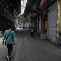 Quelques piétons marchant dans le Grand Bazar historique alors que les magasins restent fermés, à Téhéran, en Iran, le 16 juin 2025. (Crédit : Vahid Salemi/AP)