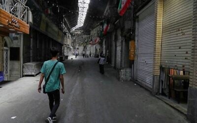Quelques piétons marchant dans le Grand Bazar historique alors que les magasins restent fermés, à Téhéran, en Iran, le 16 juin 2025. (Crédit : Vahid Salemi/AP)