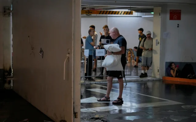 Des Israéliens se réfugient dans un parking lors d'une alerte missile iranienne, à Tel Aviv, tôt le matin du 17 juin 2025. (Crédit : AP/Baz Ratner) Des Israéliens se réfugient dans un parking lors d'une alerte missile iranienne, à Tel Aviv, tôt le matin du 17 juin 2025. (Crédit : AP/Baz Ratner)