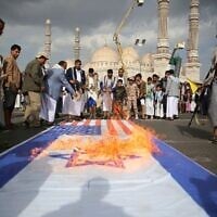 Des partisans houthis brûlant des drapeaux américains et d'Israël lors d'un rassemblement hebdomadaire anti-américain et anti-Israël, à Sanaa, au Yémen, le 20 juin 2025. (Crédit : Osamah Abdulrahman/AP)