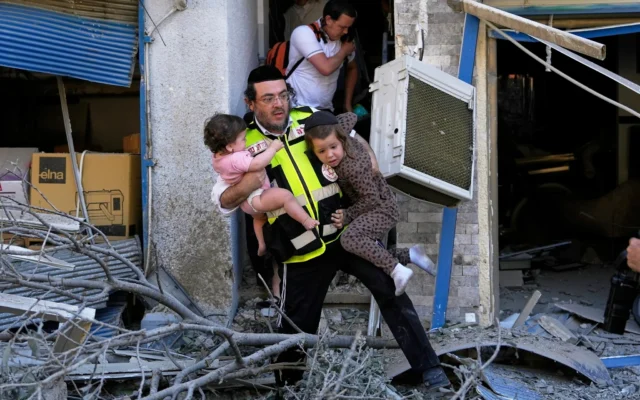 Un secouriste évacuant deux enfants du site où un missile lancé depuis l'Iran a frappé Haïfa, le 22 juin 2025. (Crédit : Baz Ratner/AP)