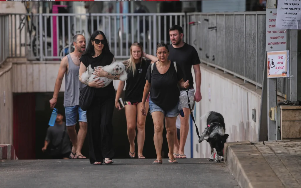 Des personnes quittant un parking souterrain où elles s'étaient réfugiées après une alerte aérienne annonçant des frappes de missiles iraniens, à Tel Aviv, en Israël, le 24 juin 2025. (Crédit : Ohad Zwigenberg/AP)