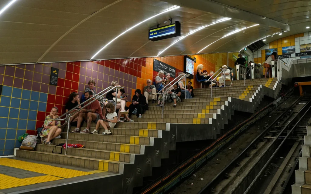 Des personnes réfugiées dans une station de métro souterraine alors que les sirènes d'alerte aérienne annoncent des frappes iraniennes, à Haïfa, en Israël, le 24 juin 2025. (Crédit : Baz Ratner/AP)