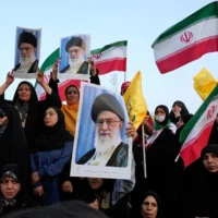 Illustration : Des manifestants iraniens brandissant des drapeaux de leur pays et des affiches du guide suprême, l'ayatollah Ali Khamenei, lors d'un rassemblement anti-américain et anti-Israël, sur la place Enqelab-e-Eslami (Révolution islamique) dans le centre-ville de Téhéran, en Iran, le 24 juin 2025. (Crédit : Vahid Salemi/AP)