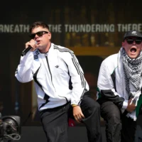 Naoise O Caireallain, à gauche, et Liam Og, du trio hip-hop Kneecap, se produisent lors du festival de Glastonbury à Worthy Farm, dans le Somerset, en Angleterre, le 28 juin 2025. (Crédit : Scott A Garfitt/Invision/AP)