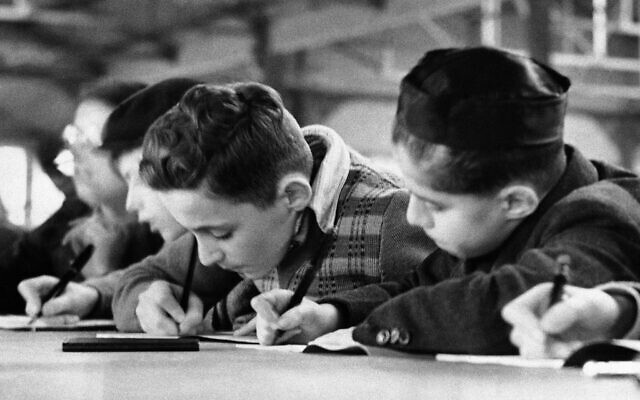 Des enfants juifs allemands suivent un cours dans une salle de classe du camp de réfugiés de Dovercourt Bay, en Angleterre, le 28 décembre 1938. (Crédit : AP)