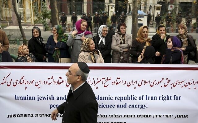 Un Juif iranien passe devant une bannière lors d’un rassemblement de la communauté juive iranienne devant un bureau de l’ONU à Téhéran, en Iran, le mardi 19 novembre 2013. (Photo AP/Ebrahim Noroozi)