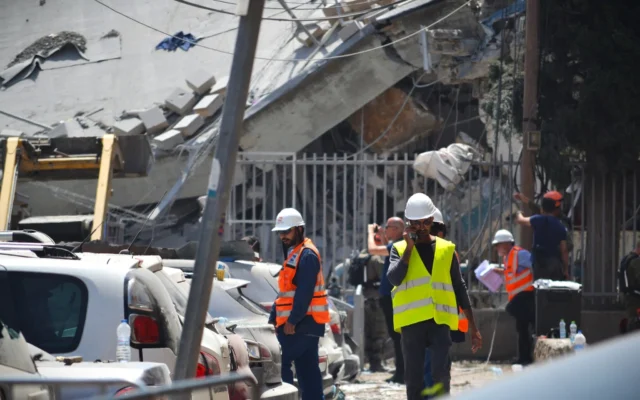 Des équipes israéliennes s'efforcent d'évaluer les dégâts et de déblayer les décombres à Bnei Brak après qu'une école locale a été touchée par un missile iranien, le 16 juin 2025. (Crédit : Stav Levaton/Times of Israel)