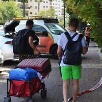 Des habitants de Petah Tikva évacuant leurs habitations détruites par une frappe iranienne en emportant quelques effets personnels, le 16 juin 2025. (Crédit : Stav Levaton/Times of Israel)