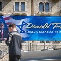 Des passants devant une affiche représentant le président américain Donald Trump dans le centre-ville de Jérusalem, le 7 mai 2025. (Crédit : Yonatan Sindel/Flash90)