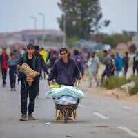 Des Palestiniens marchant près d'un point de distribution d'aide humanitaire dans le corridor de Netzarim, dans le centre de la bande de Gaza, le 9 juin 2025. (Crédit : Ali Hassan/Flash90)