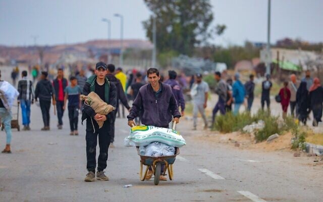 Des Palestiniens marchant près d'un point de distribution d'aide humanitaire dans le corridor de Netzarim, dans le centre de la bande de Gaza, le 9 juin 2025. (Crédit : Ali Hassan/Flash90)