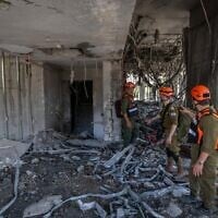 Les forces de sécurité et de secours israéliennes sur les lieux où un missile balistique tiré depuis l'Iran a frappé et causé des dégâts, à Ramat Gan, le 19 juin 2025. (Crédit : Chaïm Goldberg/Flash90)