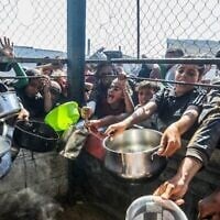 Des Palestiniens attendent de recevoir un repas chaud préparé par des bénévoles, à Khan Younès, dans le sud de la bande de Gaza, le 20 juin 2025. (Crédit : Abed Rahim Khatib/Flash90)