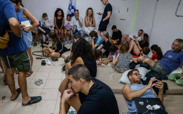 Les gens à l'abri alors que la sirène d'alerte annonce l'arrivée de missiles tirés depuis l'Iran, dans un abri antiatomique public, à Tel Aviv, le 20 juin 2025. (Crédit : Yehoshua Yosef/Flash90)