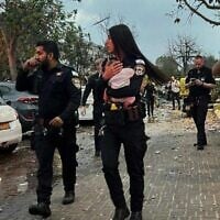 Une policière tenant dans ses bras un bébé de trois mois après l'avoir sorti des décombres d'une maison touchée par un missile iranien, à Rishon Lezion, le 14 juin 2025. (Crédit : Police israélienne)