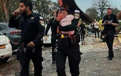 Une policière tenant dans ses bras un bébé de trois mois après l'avoir sorti des décombres d'une maison touchée par un missile iranien, à Rishon Lezion, le 14 juin 2025. (Crédit : Police israélienne)