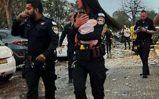 Une policière tenant dans ses bras un bébé de trois mois après l'avoir sorti des décombres d'une maison touchée par un missile iranien, à Rishon Lezion, le 14 juin 2025. (Crédit : Police israélienne) Une policière tenant dans ses bras un bébé de trois mois après l'avoir sorti des décombres d'une maison touchée par un missile iranien, à Rishon Lezion, le 14 juin 2025. (Crédit : Police israélienne)