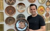 Le chaudronnier Dror Miro tient son assiette "Rising Lion"  qu'il a conçue et fabriquée dans la vieille ville d'Akko, le 16 juin 2025. (Crédit : Diana Bletter/Times of Israel)