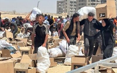 Des Gazaouis récupérant des marchandises sur un site de distribution d'aide humanitaire près de Rafah, sur une photo publiée le 5 juin 2025. (Crédit : Gaza Humanitarian Foundation)