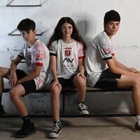 Des supporters du club de football Hapoel Jerusalem présentant leurs nouveaux maillots « extérieurs » dans un abri anti-bombes, signe des temps, le 17 juin 2025. (Crédit : Autorisation)