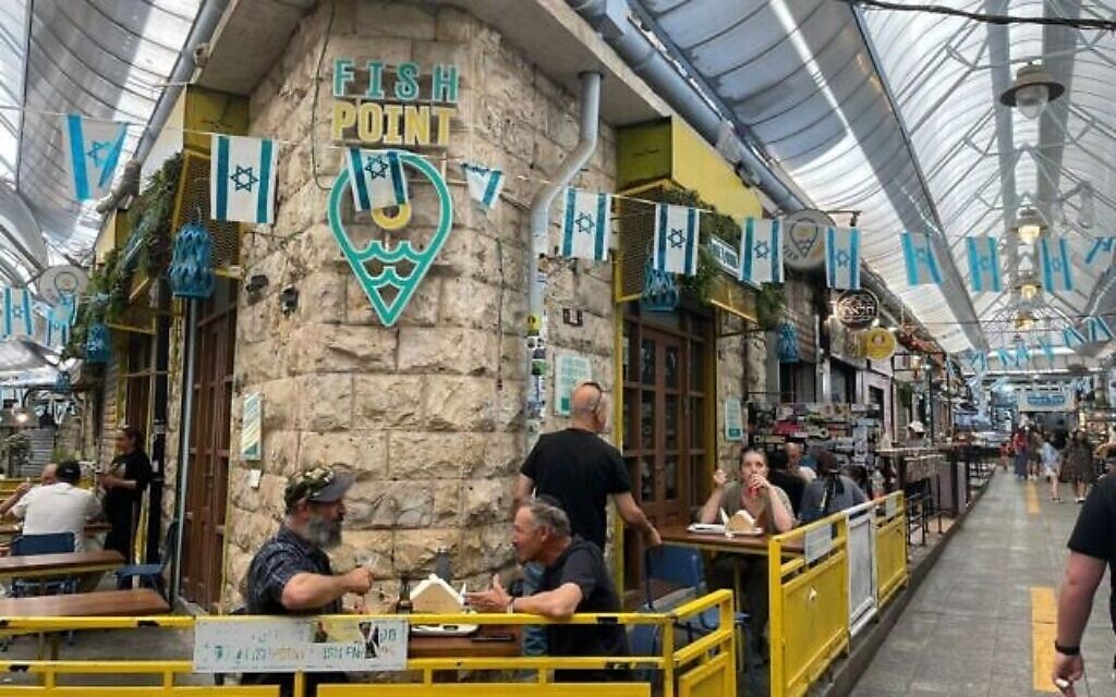 Des clients partagent un repas au marché Machane Yehuda à Jérusalem malgré la guerre avec l'Iran le 17 juin 2025. (Rossella Tercatin/Times of Israel)