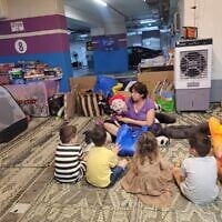 La bibliothérapeute et marionnettiste Esti Osovsky faisant du bénévolat pour l'organisation Brothers and Sisters in Israel, dans un parking transformé en abri anti-atomique public que l'organisation a aidé à équiper, dans le centre-ville de Rishon Lezion, le 23 juin 2025. (Crédit : Porte-parole, Brothers and Sisters in Israel)