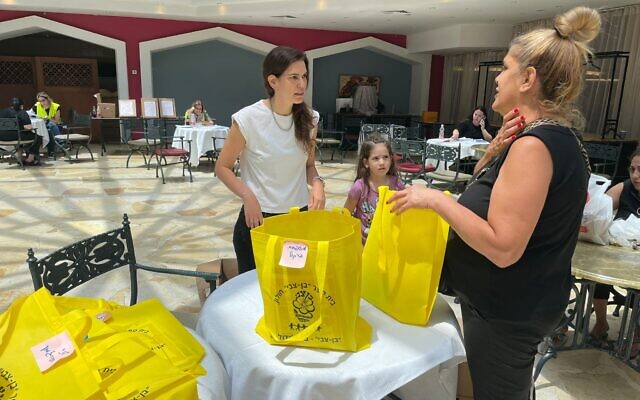 Hadas Tal, une évacuée de Holon dont la maison a été endommagée par un missile iranien, aidant une autre évacuée, à l'hôtel Leonardo, à Jerusalem, le 24 juin 2025. (Crédit : Rossella Tercatin/Times of Israel)