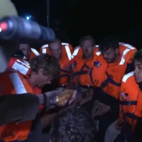 Un soldat israélien distribuant de la nourriture aux militants arrêtés à bord du Madleen après leur interception, le 9 juin 2025. (Crédit : Capture d'écran : Ministère des Affaires étrangères/X)