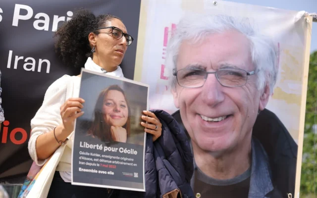 Une sympathisante tient une pancarte à l'effigie de Cécile Kohler, professeure de français détenue en Iran avec son compagnon Jacques Paris (à droite), lors d'un rassemblement en leur soutien à Paris, en France, le 14 mai 2023. (Crédit : Thomas SAMSON/AFP) Une sympathisante tient une pancarte à l'effigie de Cécile Kohler, professeure de français détenue en Iran avec son compagnon Jacques Paris (à droite), lors d'un rassemblement en leur soutien à Paris, en France, le 14 mai 2023. (Crédit : Thomas SAMSON/AFP)