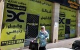 Une femme passe devant les bureaux fermés de la société d'échange Alkhalej à Ramallah, le 16 mai 2024. (Crédit : JAAFAR ASHTIYEH / AFP)
