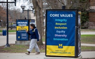Des étudiants de l'Université du Michigan sur le campus, marchant à côté d'une signalisation affichant les "valeurs fondamentales" de l'université, le 3 avril 2025, à Ann Arbor, Michigan. (Crédit : BILL PUGLIANO / GETTY IMAGES NORTH AMERICA / Getty Images via AFP)