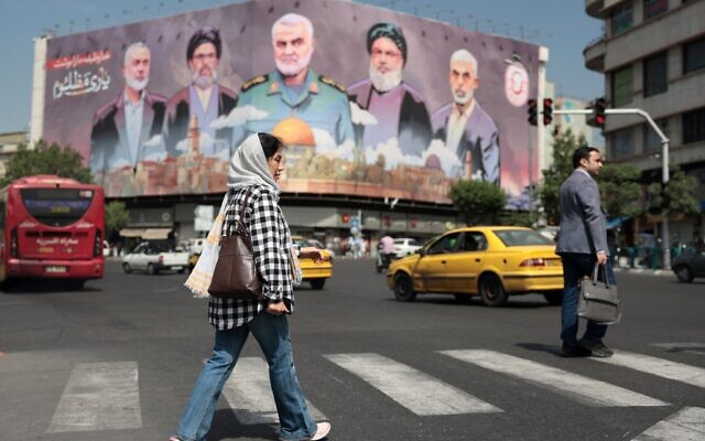 Une femme passe devant un panneau d'affichage portant les portraits de dirigeants iraniens, du Hezbollah et du Hamas tués, sur la place Enghelab de Téhéran, le 11 mai 2025. (Crédit : ATTA KENARE / AFP)