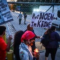 Des personnes tenant des bougies et des pancartes sur lesquelles on peut lire « Put Noem in Krome » (Mettez Noem à Krome) lors d'une veillée de protestation contre la détention et les expulsions massives menées par les services américains de l'Immigration and Customs Enforcement (ICE), devant le centre de détention de Krome, à Miami, le 24 mai 2025. (Crédit : Giorgio Viera/AFP)