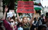 Un manifestant brandit une pancarte sur laquelle on peut lire « Les terroristes ne taguent pas, ils bombardent des enfants » lors d'un rassemblement en faveur du groupe pro-palestinien et anti-israélien Palestine Action, à Trafalgar Square, à Londres, le 23 juin 2025. (Crédit : Henry Nicholls / AFP)