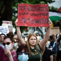 Un manifestant brandit une pancarte sur laquelle on peut lire « Les terroristes ne taguent pas, ils bombardent des enfants » lors d'un rassemblement en faveur du groupe pro-palestinien et anti-israélien Palestine Action, à Trafalgar Square, à Londres, le 23 juin 2025. (Crédit : Henry Nicholls / AFP)