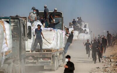 Des Palestiniens armés s'assoient sur des camions transportant de l'aide humanitaire près du poste frontière de Zikim entre Israël et Beit Lahia dans le nord de la bande de Gaza, le 25 juin 2025. (Crédit : Ali Qariqa/Flash90) Des Palestiniens armés s'assoient sur des camions transportant de l'aide humanitaire près du poste frontière de Zikim entre Israël et Beit Lahia dans le nord de la bande de Gaza, le 25 juin 2025. (Crédit : Ali Qariqa/Flash90)