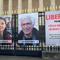 Les portraits de Cécile Kohler, actuellement emprisonnée en Iran, et de son compagnon Jacques Paris, ainsi qu'une pancarte indiquant "Liberté pour Cécile Kohler et Jacques Paris détenus arbitrairement en Iran depuis plus de deux ans dans des conditions épouvantables" devant le Palais Bourbon, l'Assemblée nationale française, à Paris, le 25 mars 2025. (Crédit : Bertrand Guay/AFP)