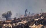 Des résidents d’implantations masqués lançant des pierres sur des Palestiniens depuis le sommet d'une colline, dans le village de Sinjil, en Cisjordanie, le 4 juillet 2025. (Crédit : John Wessels/AFP)