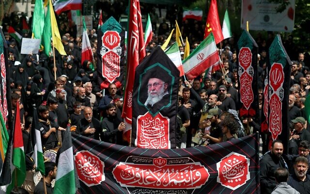 Des Iraniens brandissant une banderole à l'effigie du guide suprême, l'ayatollah Ali Khamenei, lors d'un rassemblement en son soutien, alors que les musulmans chiites assistent au rituel funèbre du « Tasua » (neuvième jour) pour commémorer le martyre de l'imam Hussein, petit-fils du prophète Mahomet, pendant le mois islamique du Muharram, avant l'Achoura, le 5 janvier 2025. (Crédit : AFP) Des Iraniens brandissant une banderole à l'effigie du guide suprême, l'ayatollah Ali Khamenei, lors d'un rassemblement en son soutien, alors que les musulmans chiites assistent au rituel funèbre du « Tasua » (neuvième jour) pour commémorer le martyre de l'imam Hussein, petit-fils du prophète Mahomet, pendant le mois islamique du Muharram, avant l'Achoura, le 5 janvier 2025. (Crédit : AFP)